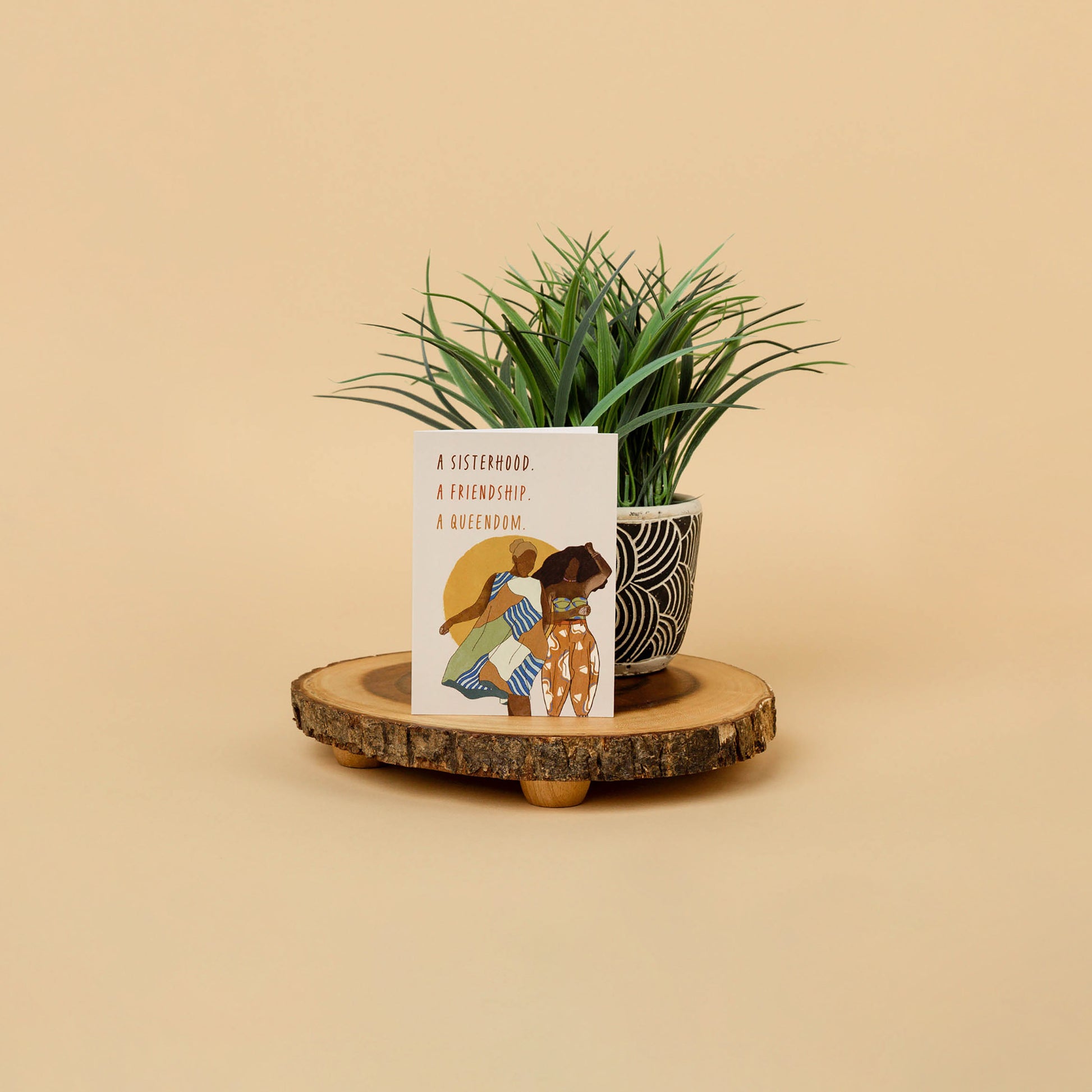 greeting card of two black women representing friendship balancing on wood decor against house plant